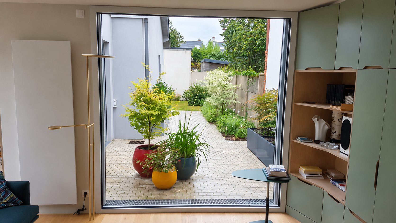 Cour aménagée à Nantes vue depuis l’intérieur de la maison, avec pots de plantes et pavage
